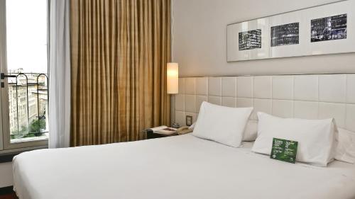 a hotel room with a large white bed and a window at 725 Continental Hotel in Buenos Aires