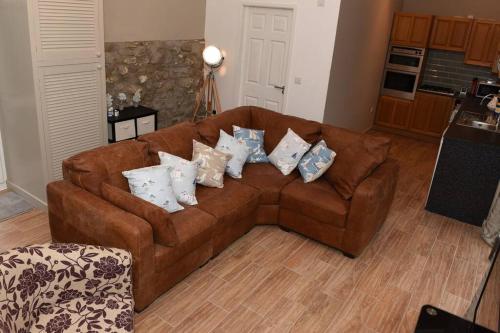 un sofá marrón con almohadas en la sala de estar en Orchard Cottage, Pwllheli, North Wales, en Pwllheli
