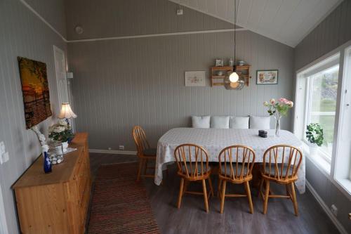 a dining room with a table and four chairs at Hytte ved sjøen in Napp