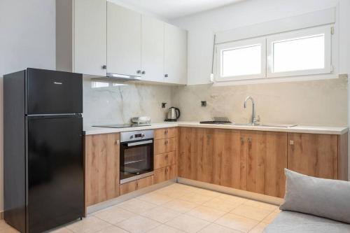a kitchen with a black refrigerator and wooden cabinets at Privilegio Studio 3 in Kanali