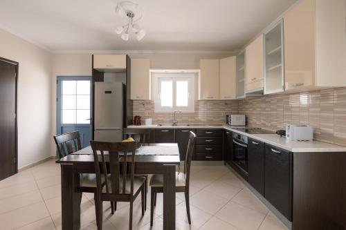 una cucina con tavolo, sedie e frigorifero di Mandi's Apartments a Karavádhos