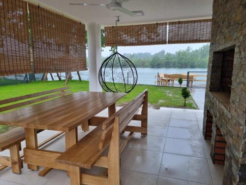 a wooden table and bench with a view of the water at Drinska prica 2 in Loznica
