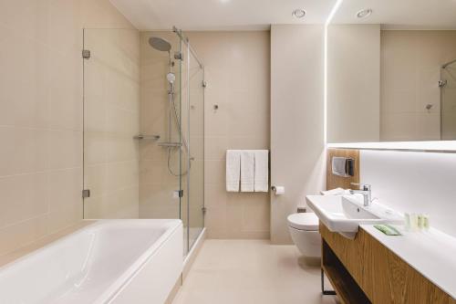 a bathroom with a tub and a sink and a toilet at Courtyard by Marriott Warsaw Airport in Warsaw