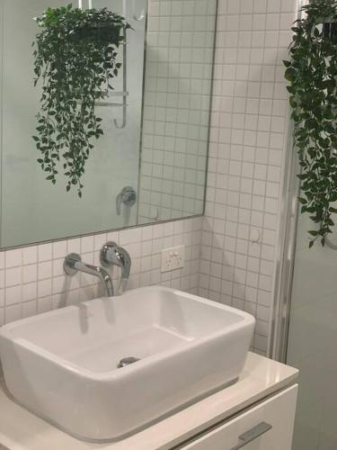 lavabo blanco en el baño con espejo en Carlton Stunning View Apartment with Free Parking -2 en Melbourne