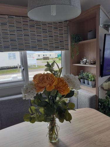un vaso di fiori seduto su un tavolo di Golden Sands Retreat a Mablethorpe