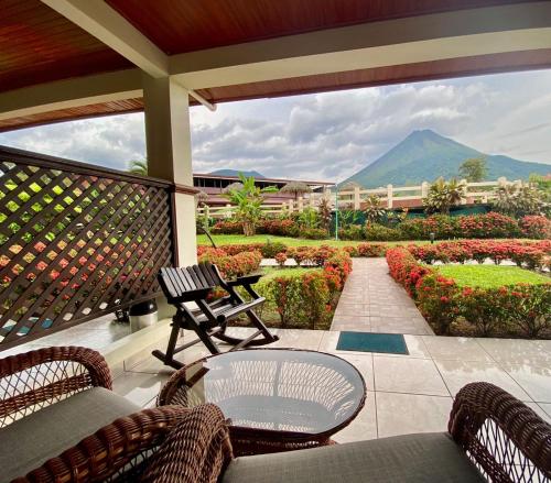 um alpendre com cadeiras e uma mesa e vista para uma montanha em Hotel La Pradera del Arenal em La Fortuna