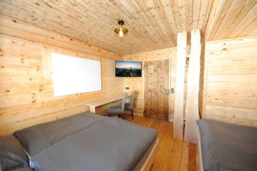 a bedroom with a bed and a desk in a wooden room at Ferienhof Holzmeister in Sankt Jakob in Haus