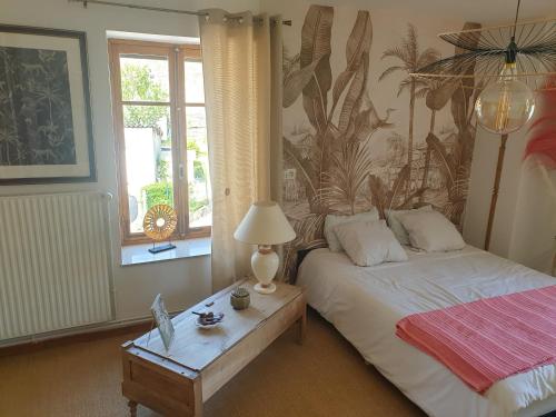 een slaapkamer met een bed en een tafel met een lamp bij LA FOLLE PARENTHESE in Vireux-Molhain