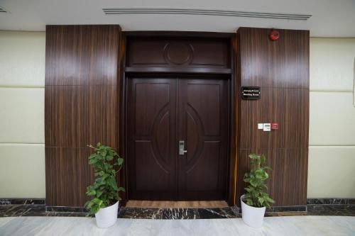 a wooden door with two potted plants in front of it at رؤوم إن للشقق الفندقية-Raoum Inn Hotel Apartments-Buraydah in Buraydah