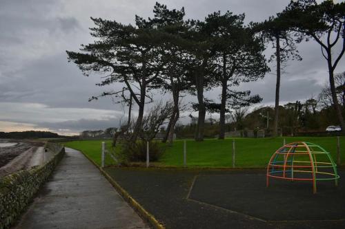 a playground in a park with trees and a field at Ballywalter Beach House in Ballywalter