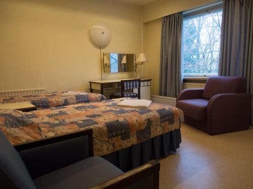 um quarto de hotel com uma cama e uma cadeira em Laitilan Kievari em Laitila