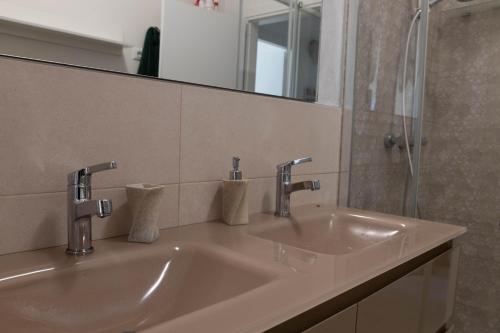 un lavandino in bagno con due rubinetti e uno specchio di Estate a Desenzano del Garda