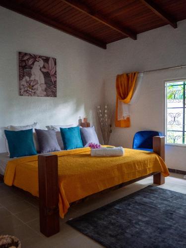 a bedroom with a large bed with yellow and blue pillows at La petite Maison Bakov’ in Montjoly