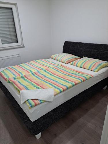 een ongeëvenaard bed met een kleurrijke deken erop bij Apartman Knežević in Donja Varoš