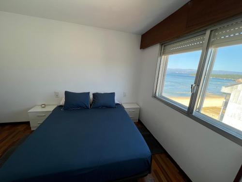 um quarto com uma cama azul e 2 janelas em Playa Compostela em Vilagarcía de Arousa