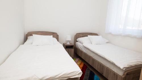two twin beds in a room with a window at River&Lake Luxury I. Apartman in Sárvár