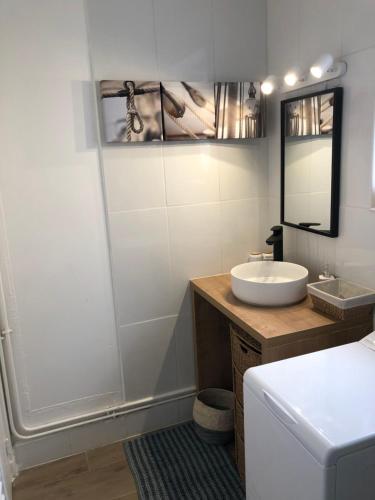 ein weißes Badezimmer mit einem Waschbecken und einem Spiegel in der Unterkunft Le Parc plein centre près de la Grande plage in Carnac