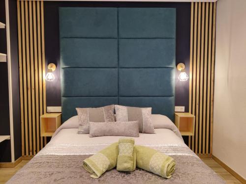 a bedroom with a large bed with a blue headboard at Duerme a gusto - Tu habitación acogedora en Torredonjimeno in Torredonjimeno