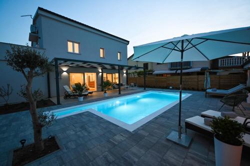 uma piscina em frente a uma casa com um guarda-chuva em Villa Adria em Privlaka