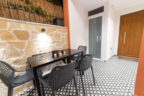 a dining room with a table and chairs and a stone wall at Bella Vasilica Luxury Apartments in Parga