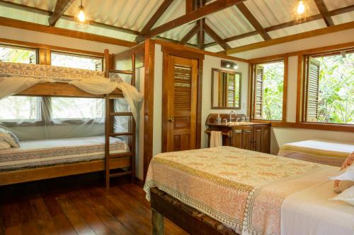 a bedroom with two bunk beds and a bathroom at Casa Cayuco Eco-Adventure Lodge in Bocas del Toro