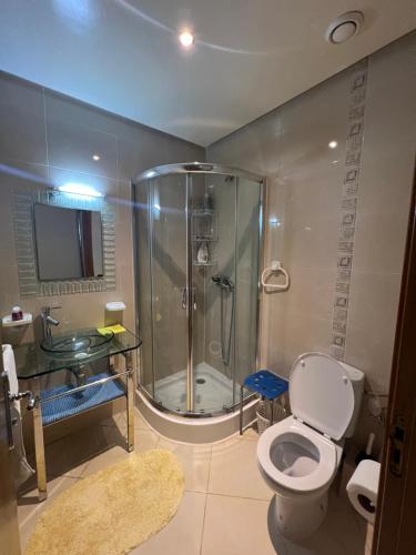 een badkamer met een douche, een toilet en een wastafel bij Appartement Assilah marina golf in Asilah