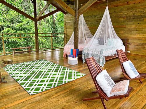 a bedroom with a bed and two chairs in a cabin at Casa Cayuco Eco-Adventure Lodge in Bocas del Toro