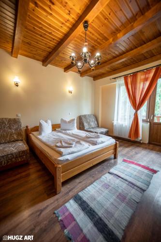a bedroom with a bed and a couch and a chandelier at Pensiunea Flora in Băile Tuşnad