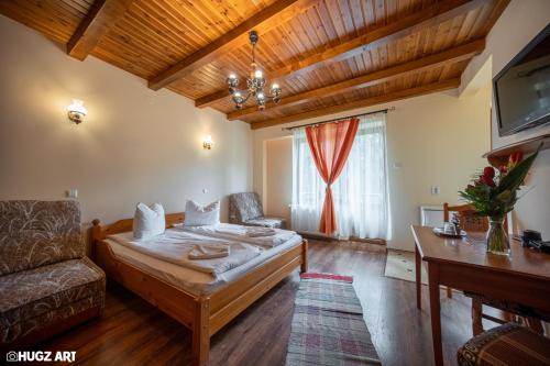 a bedroom with a bed and a couch and a tv at Pensiunea Flora in Băile Tuşnad