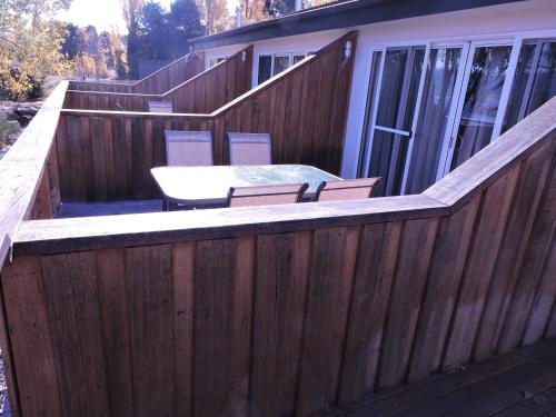 a wooden fence with a table and chairs on a deck at Siesta Villa in Jindabyne