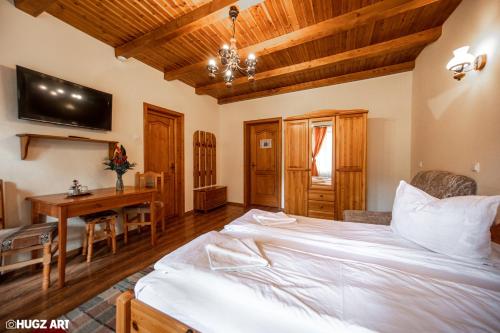 a bedroom with a bed and a desk and a table at Pensiunea Flora in Băile Tuşnad