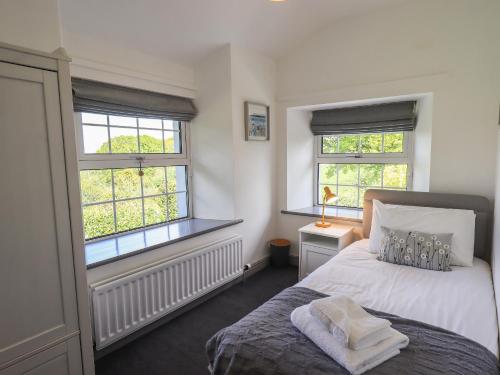 a bedroom with a bed and two windows at Greenstyles in Bowness-on-Windermere