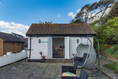 a chair sitting in front of a small shed at Pebbles by Bloom Stays in Sandgate