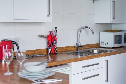 a kitchen with a sink and a counter with wine glasses at Pebbles by Bloom Stays in Sandgate