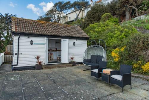 a small white shed with two chairs in front of it at Pebbles by Bloom Stays in Sandgate
