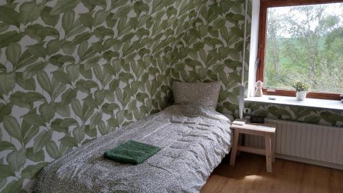 a bedroom with a bed with a green leafy wallpaper at Cosy Farmhouse Single bedroom in Stege