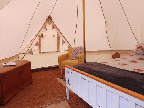 a bedroom with a tent with a bed and a chair at Chestnut Luxury emperor bell tent with log burner in Liverton