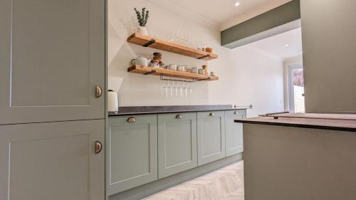 a kitchen with white cabinets and a counter top at The Retreat in Holland-on-Sea