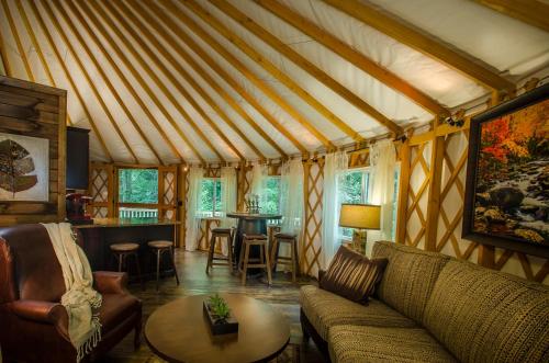 a living room with a couch and a table at Spring Ridge Luxury Yurt - Creekside Glamping with Private Hot Tub in Topton
