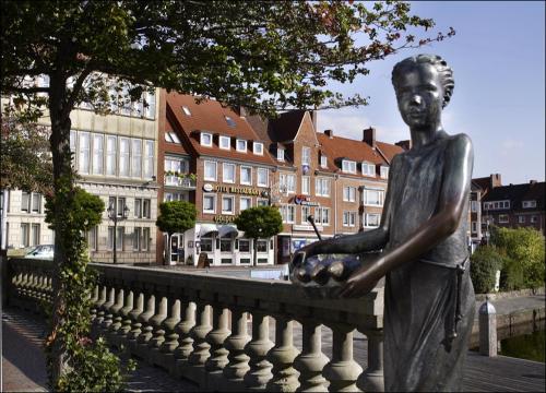 een standbeeld van een man die op een hek staat bij Restaurant Hotel Goldener Adler in Emden