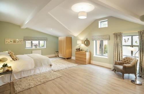 a large bedroom with a large bed and a chair at The Gardener's Bothy Shropshire in Weston under Lizard