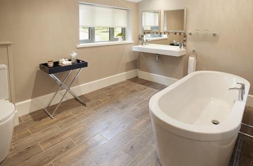 ein Badezimmer mit einer Badewanne, einem Waschbecken und einem WC in der Unterkunft The Gardener's Bothy Shropshire in Weston under Lizard