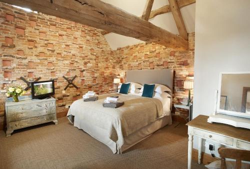 Pauntley的住宿－The Dovecote，一间卧室设有一张大床和砖墙