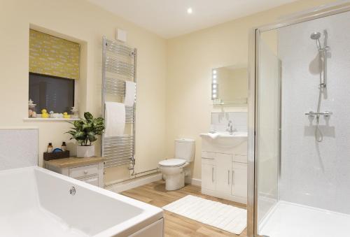ein Badezimmer mit einer Badewanne, einem WC und einem Waschbecken in der Unterkunft Holywell House 8 Guests in Wellington
