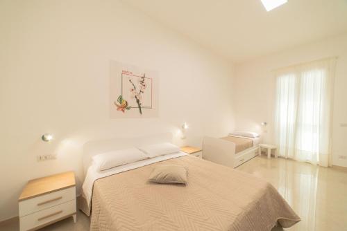 a white bedroom with a bed and a window at B&B MANDORLO BIANCO in Avola