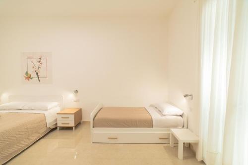 two beds in a bedroom with white walls at B&B MANDORLO BIANCO in Avola
