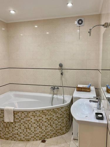 a bathroom with a bath tub and a sink at Cozy apartment next to the park in Ternopilʼ