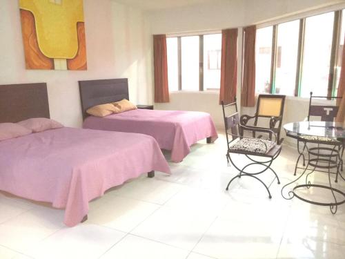 um quarto com 2 camas, uma mesa e cadeiras em Deptos Santa lucia em Mérida