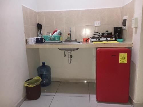 uma pequena cozinha com um lavatório e um frigorífico vermelho em Deptos Santa lucia em Mérida