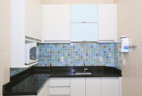 una cucina con armadi bianchi, lavandino e forno a microonde di Unhotel - Apartamento de Temporada em Ipanema com 4 quartos a Rio de Janeiro
